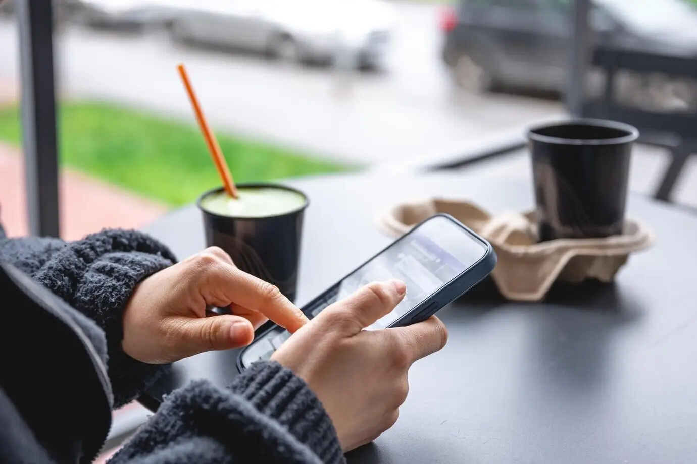 Close-up of a woman sitting on the terrace of a cafe using a smartphone.