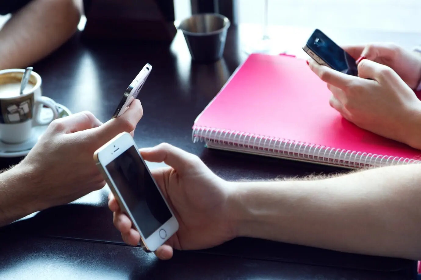 A group of friends at a cafe using a mobile phone.
